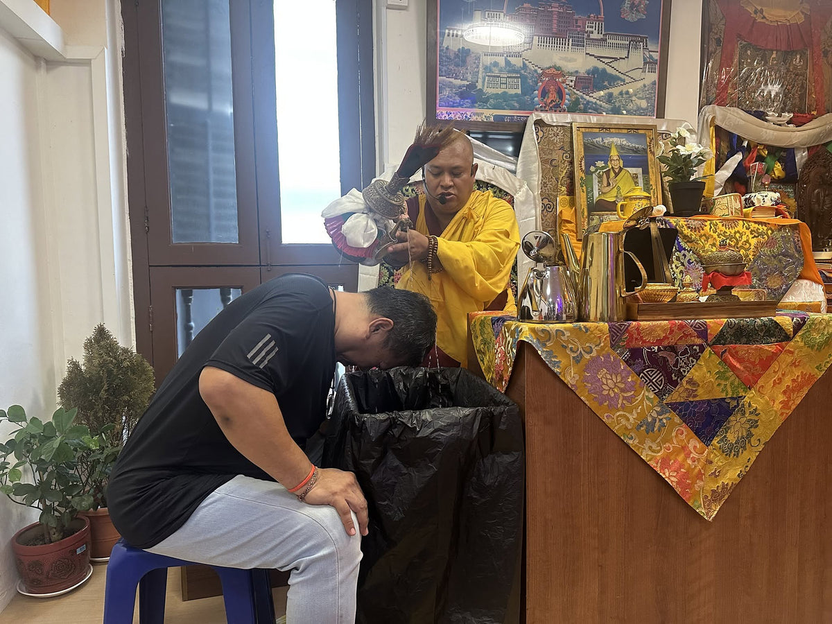 Rinpoche pouring blessed water over a devotee during the Water Purification Puja